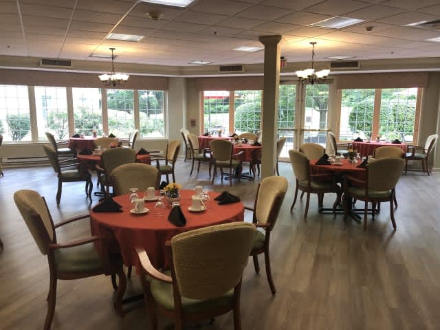 An elegantly set dining room with multiple tables and large windows.
