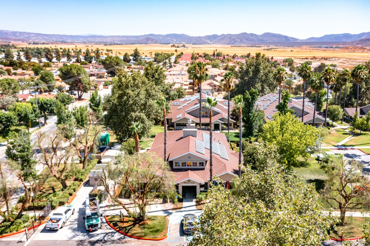 Aerial view of a suburban neighborhood with houses, trees, and mountains in the background.