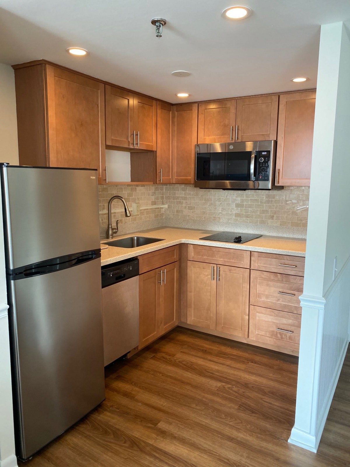 A modern apartment kitchen with wooden cabinets and stainless steel appliances.