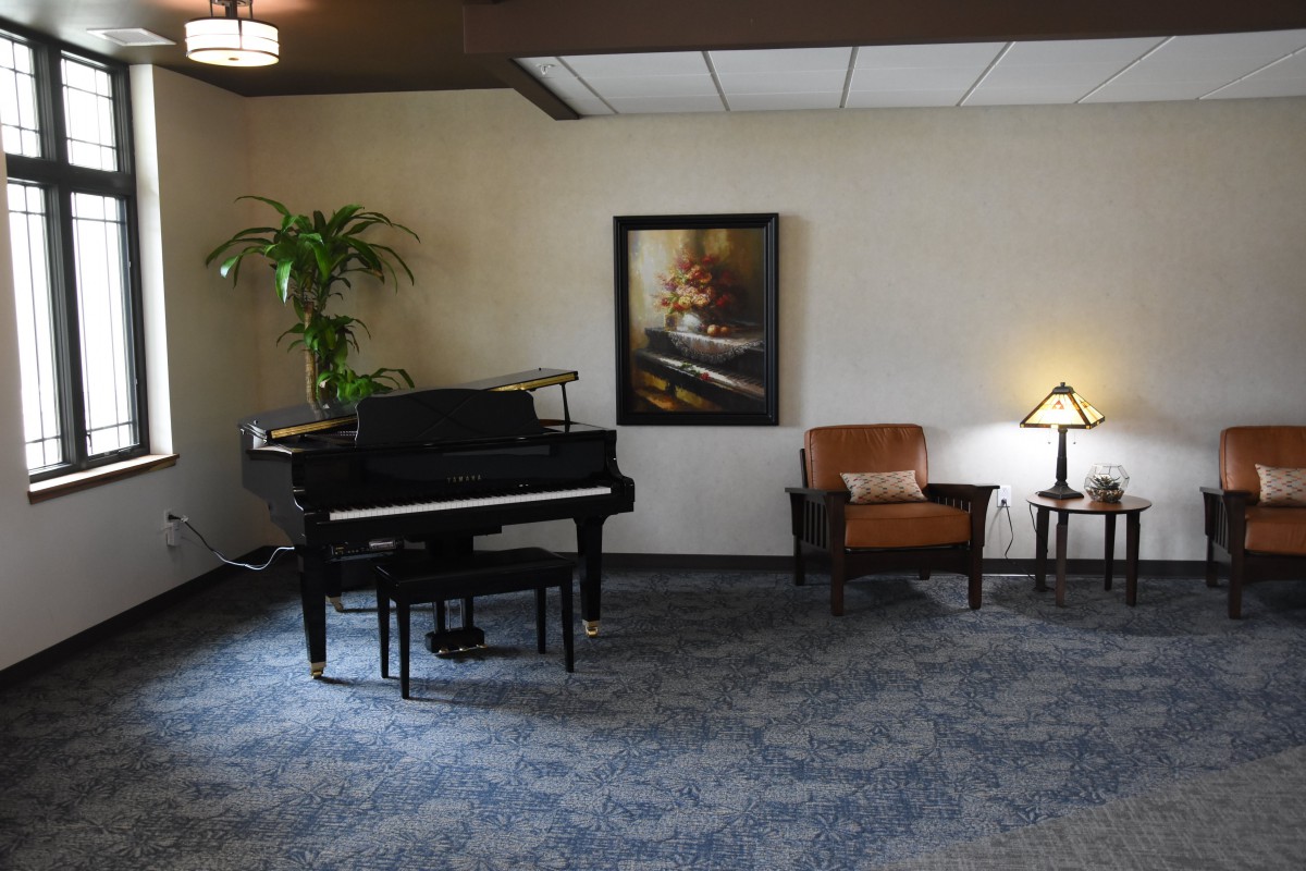 A cozy living space featuring a grand piano, artwork on the wall, and comfortable seating with ambient lighting.