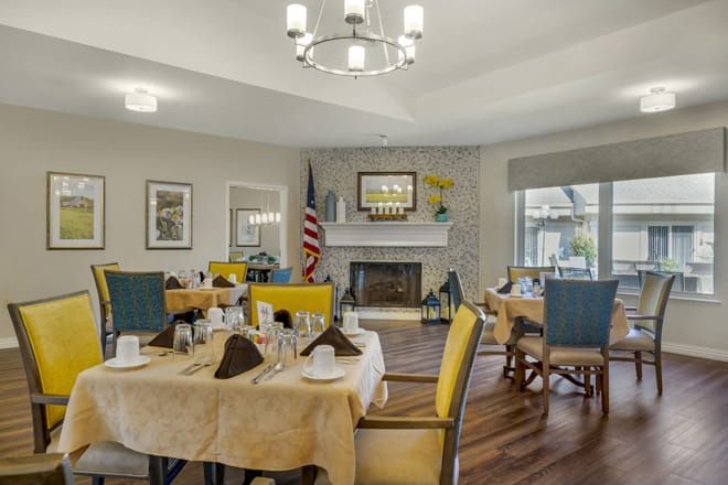 A cozy dining room with neatly set tables and a fireplace, creating an inviting atmosphere.