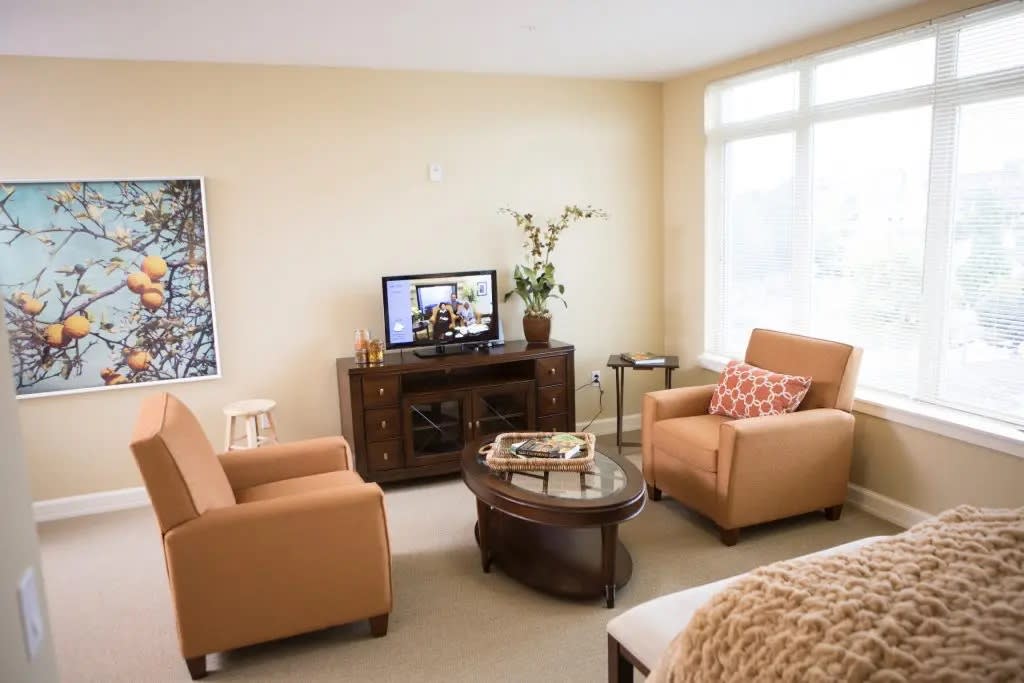 A cozy living room with two armchairs, a wooden coffee table, and a TV stand, creating an inviting and comfortable atmosphere.