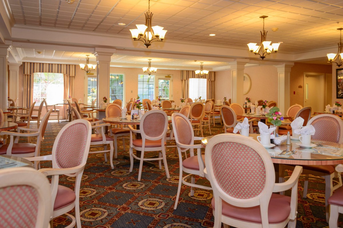 Elegant dining room with pink chairs and set tables.