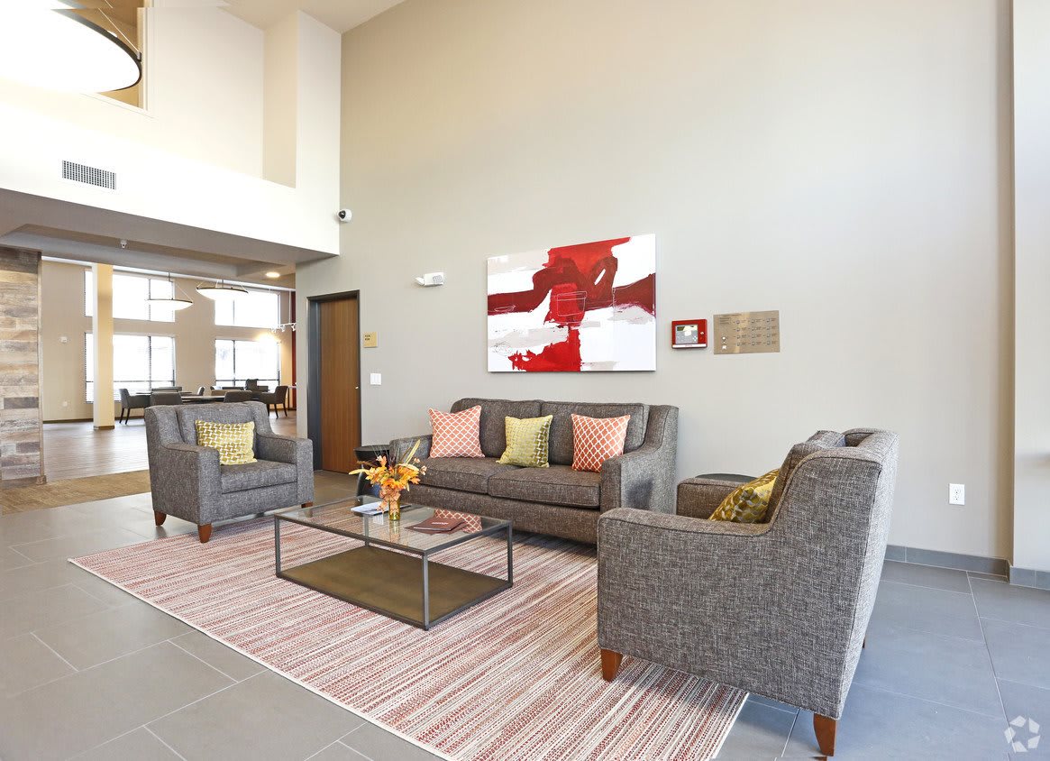 A modern living room with gray sofas, colorful cushions, abstract artwork on the wall, and a coffee table on a striped rug.