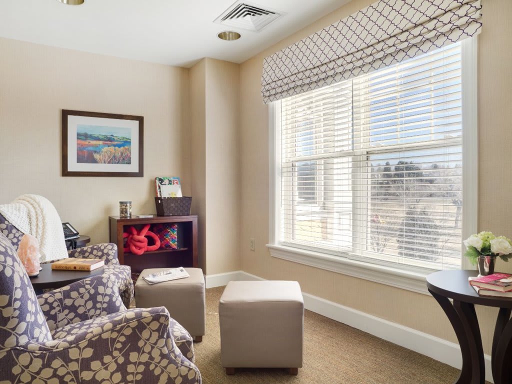 A cozy living room with ample natural light streaming through the large window, featuring comfortable seating and subtle decor.