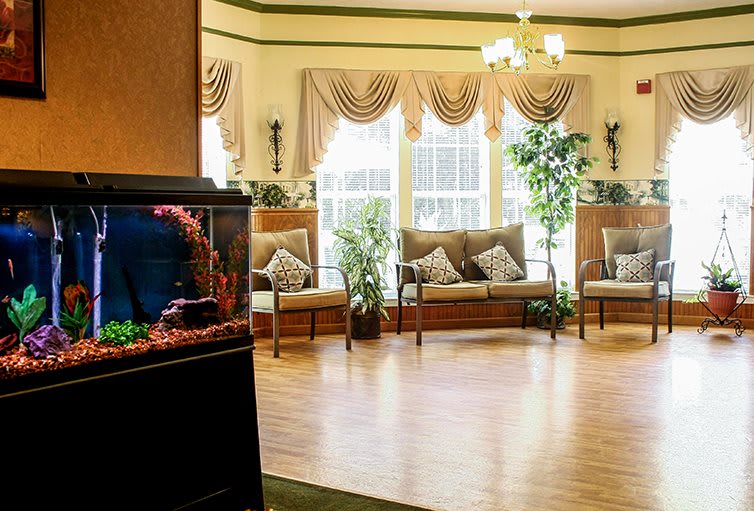A well-lit lobby with comfortable seating, featuring a fish tank and decorative plants.