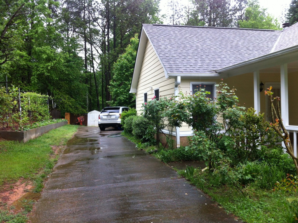 A suburban house with a driveway and garden on a rainy day.