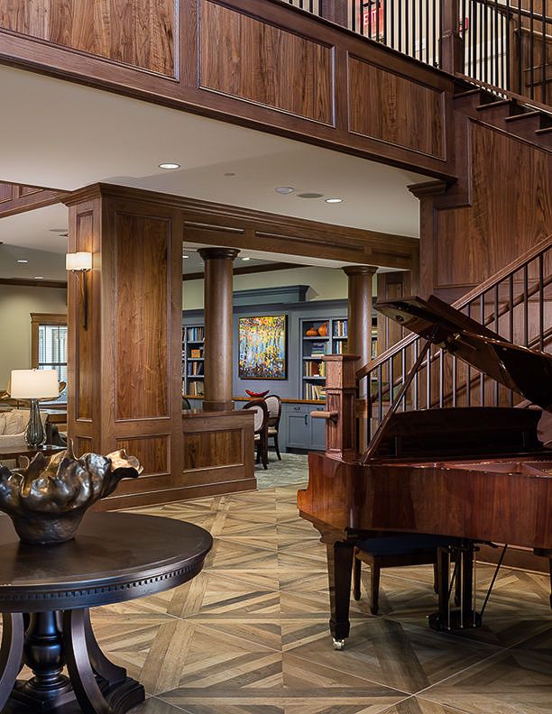 A sophisticated interior featuring a grand piano, wood paneling, and a cozy library setting.