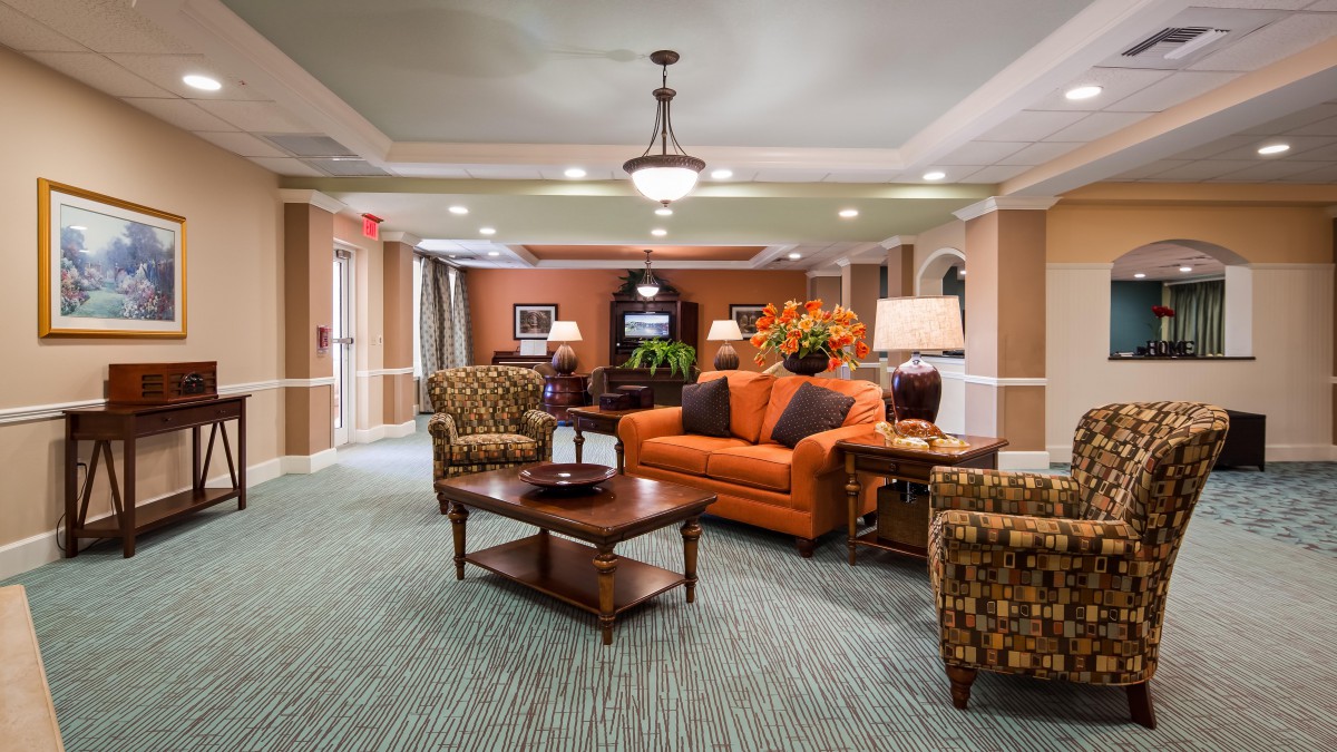 A cozy living room with a warm color scheme featuring an orange sofa and wooden furniture.