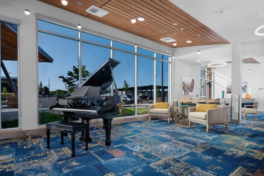 A modern lobby interior featuring a grand piano, large windows, and a stylish seating area.