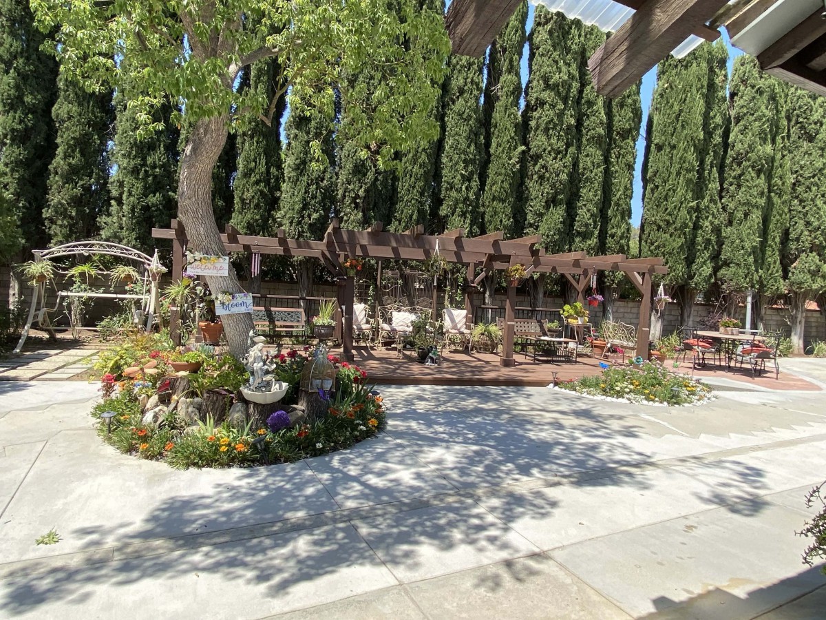 A serene garden setting with a pathway surrounded by lush greenery and flowers.