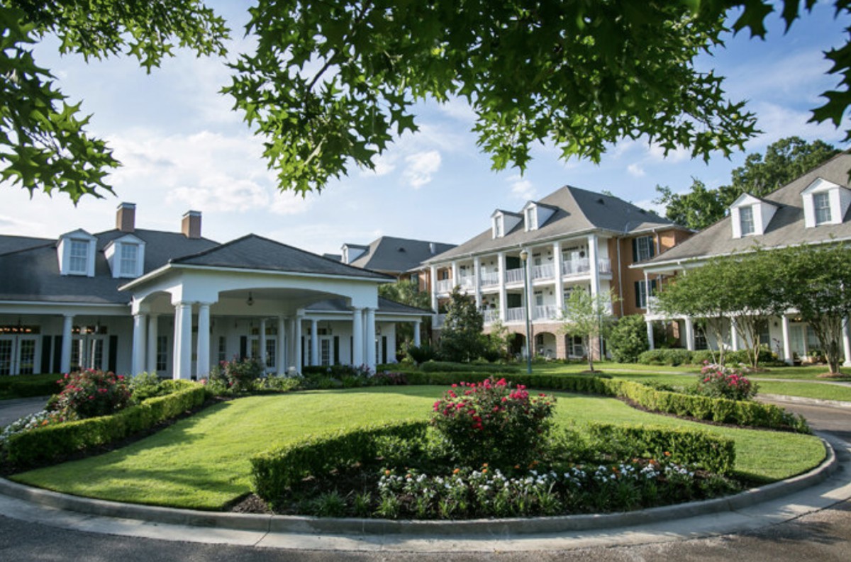 A luxurious hotel with classic architecture surrounded by lush greenery.