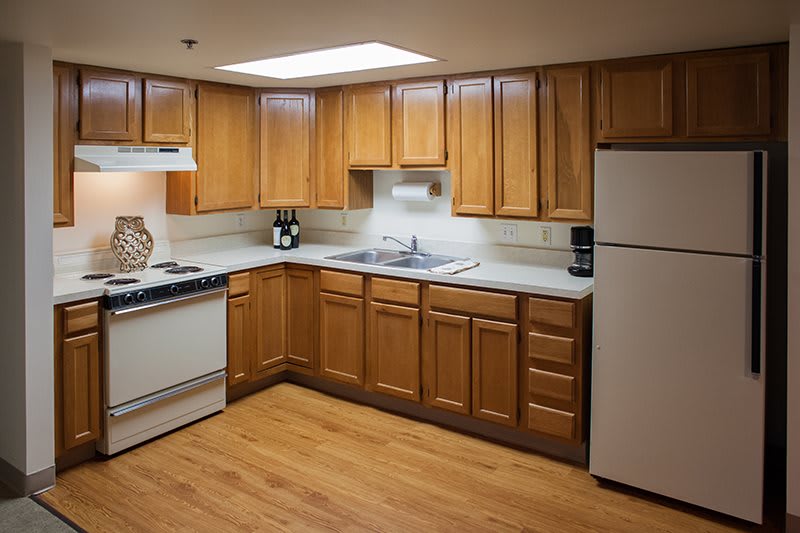A well-organized kitchen with wooden cabinets, a refrigerator, stove, and sink.