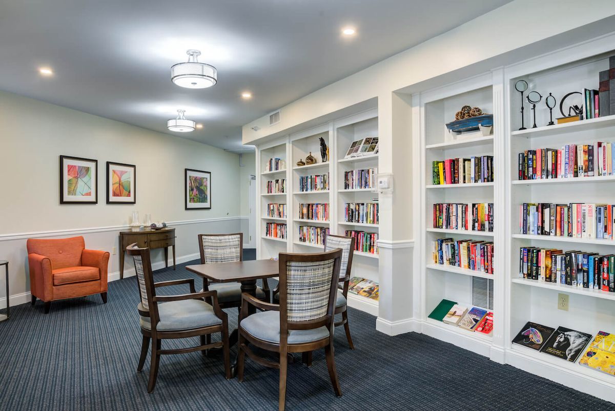 A cozy library with bookshelves, a table, and chairs for reading.