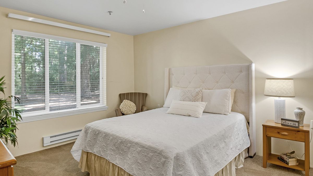 A cozy bedroom with a neatly made bed and a window letting in natural light.