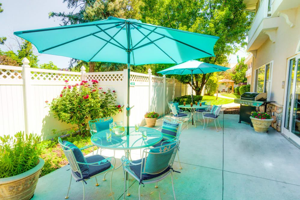 A sunny backyard patio with comfortable outdoor seating and turquoise umbrellas.