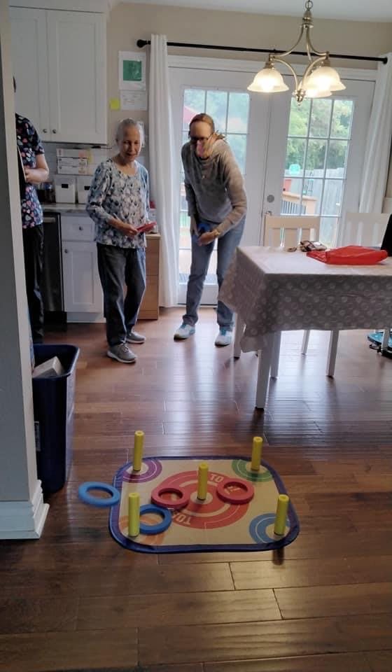 Two people enjoying an indoor ring toss game.
