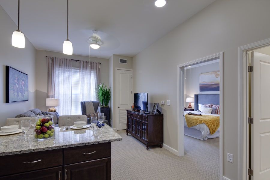 Modern apartment interior with an open kitchen and living room, featuring a view into the bedroom.