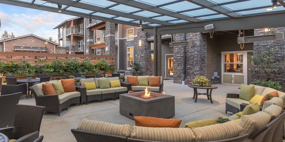 A modern outdoor seating area with a fire pit and colorful cushions in an apartment complex.