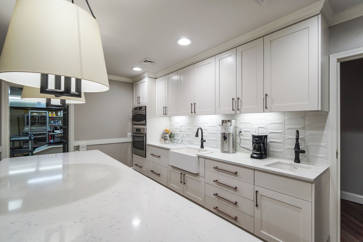 A modern kitchen with white cabinets and a sleek design, featuring a subway tile backsplash and stainless steel appliances.