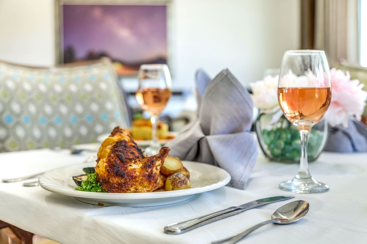 An elegant dining setup featuring a gourmet roast chicken dish served with wine.