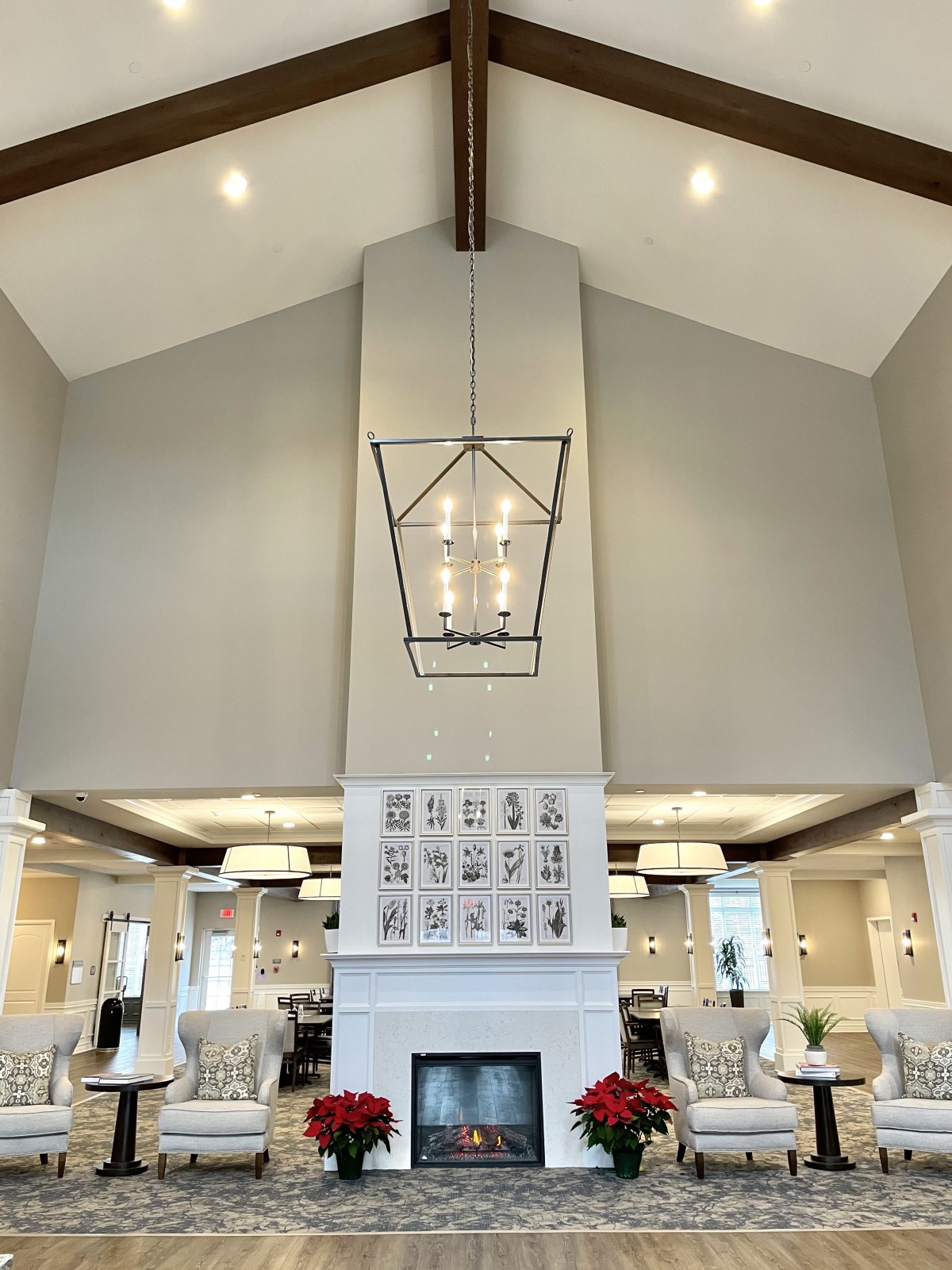 A modern living room with a high ceiling, featuring a central chandelier and a fireplace.