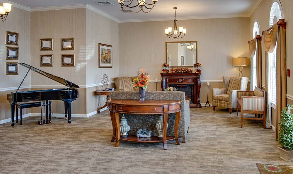 A sophisticated living room with elegant furniture, a piano, and a fireplace.