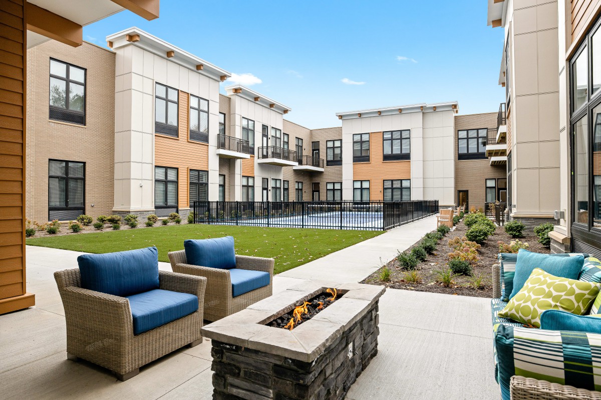 Modern apartment complex courtyard with comfortable outdoor seating and a fire pit.