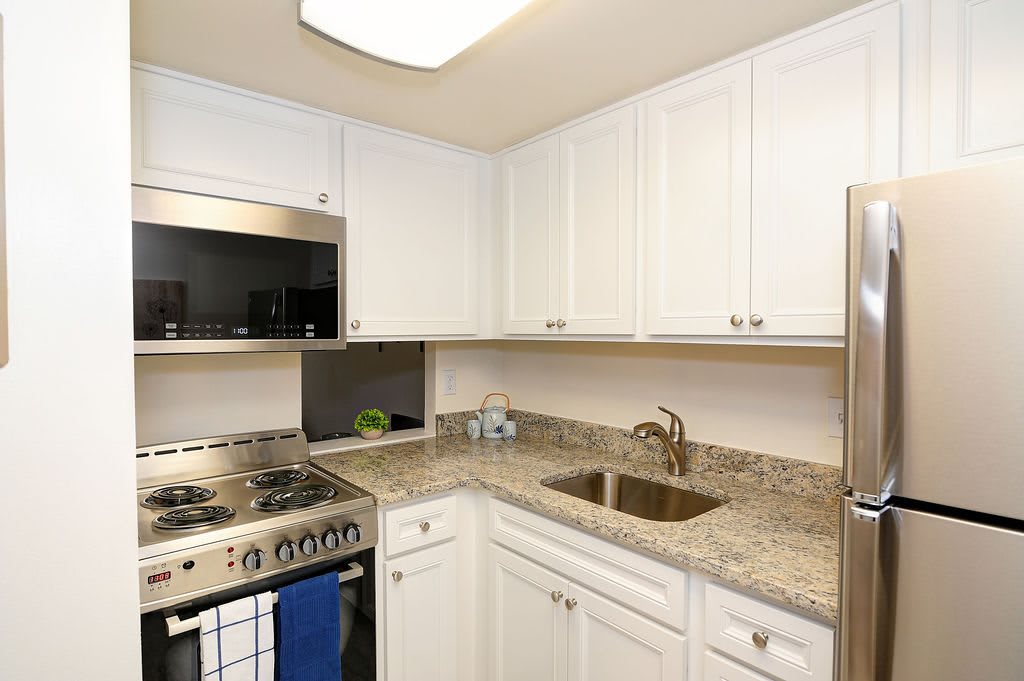 A modern kitchen with white cabinets and a granite countertop.