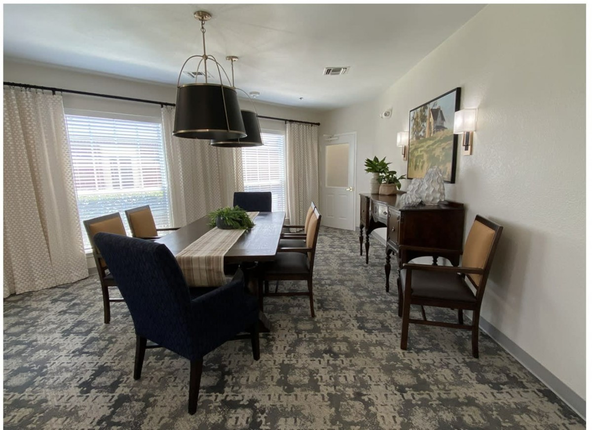 A modern dining room with a large table, chairs, and stylish lighting.
