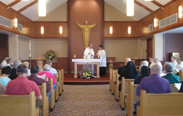 A church service with a priest conducting mass at the altar, attended by congregants.