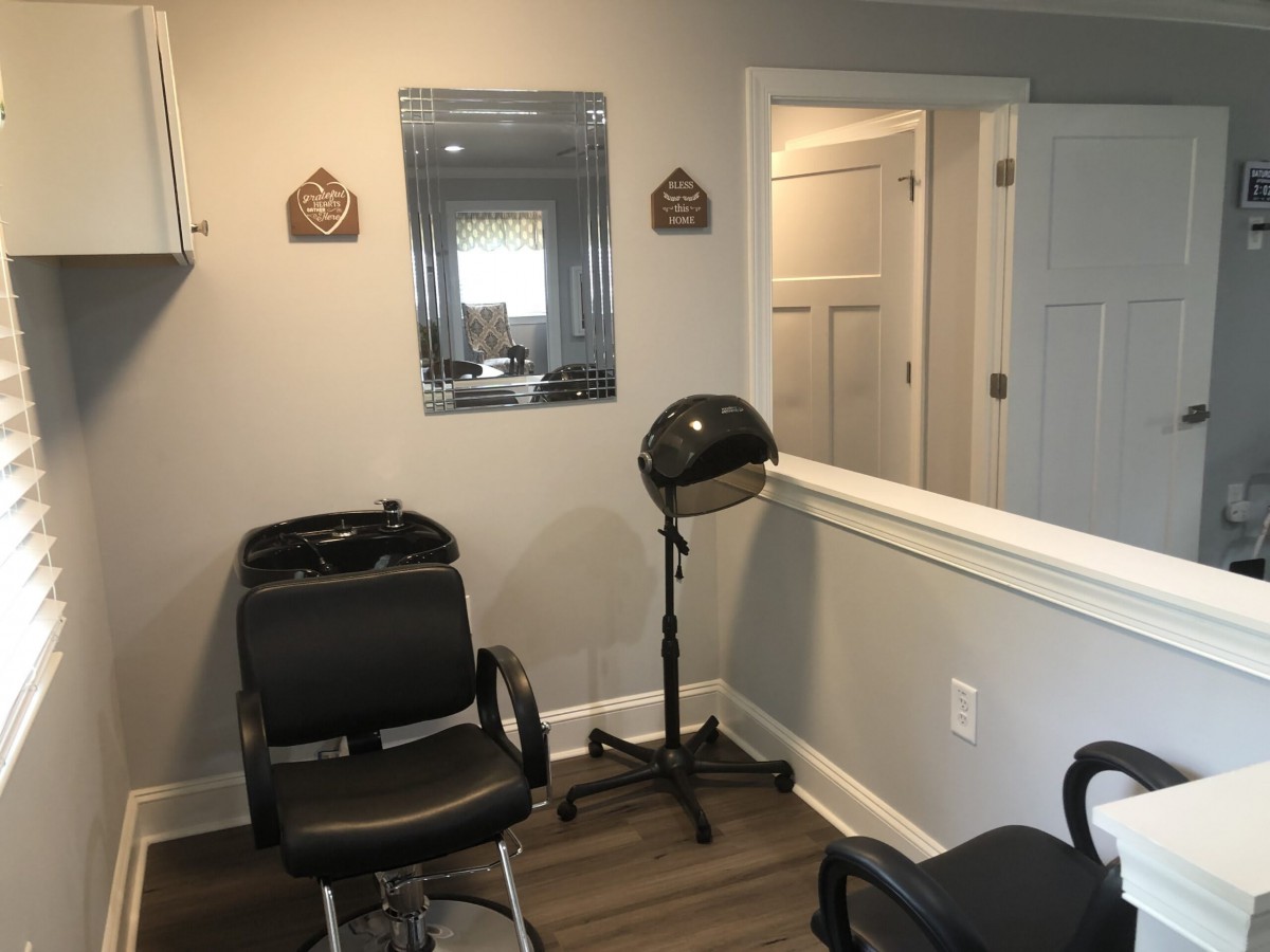 A cozy hair salon interior with chairs, a mirror, and a hair dryer.