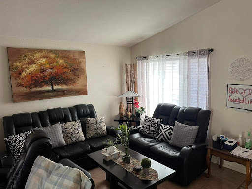 A cozy living room featuring black leather sofas, decorative cushions, and a vibrant piece of artwork.