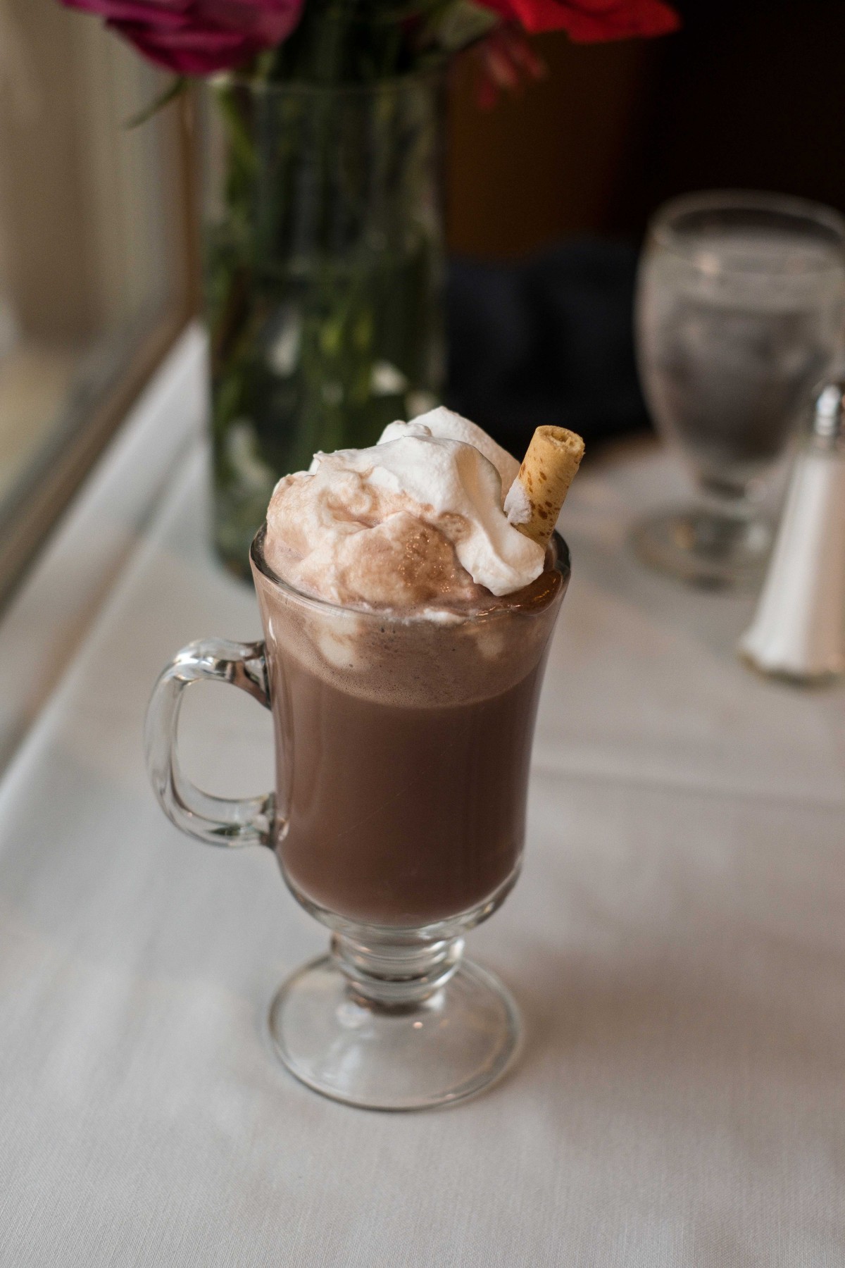 A delicious glass of hot chocolate topped with whipped cream and a wafer stick.