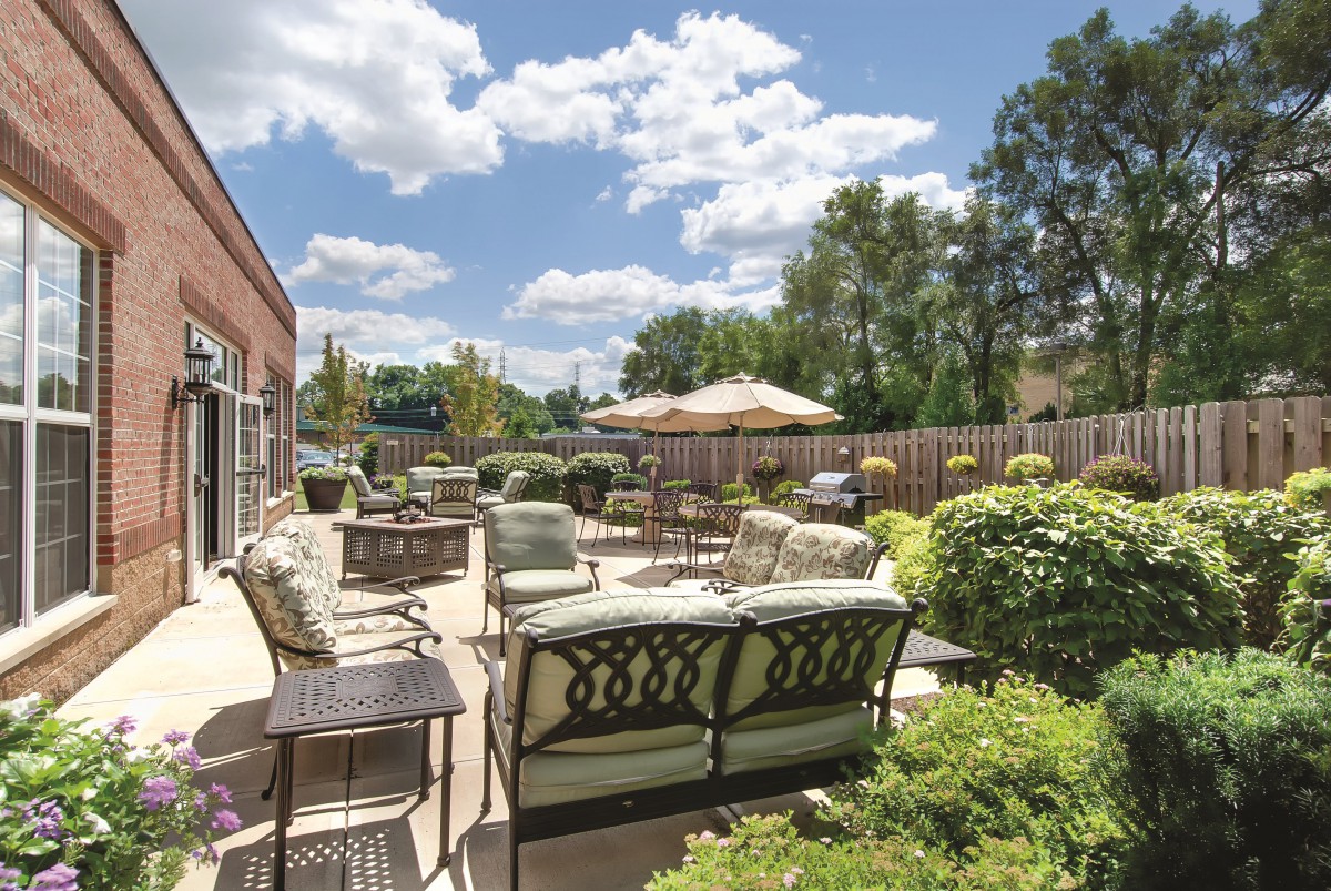 A spacious patio with comfortable outdoor seating and lush greenery on a sunny day.