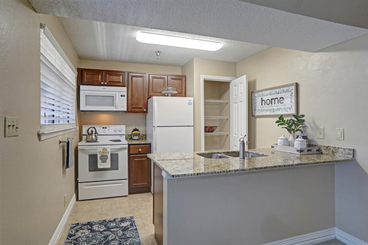 A modern kitchen interior with wood cabinets and white appliances.