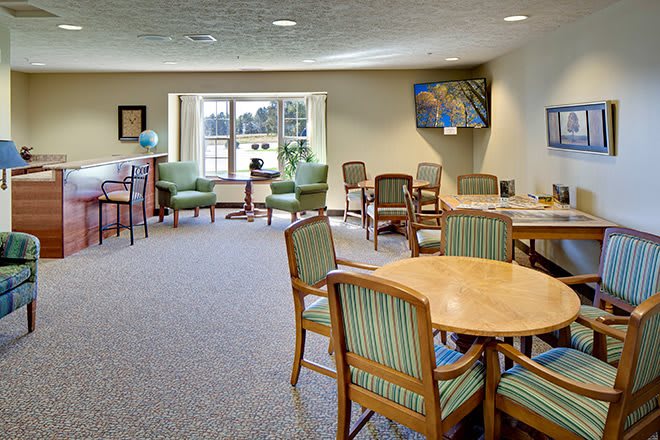 A spacious and well-lit seating area with chairs and tables, featuring large windows that let in natural light.