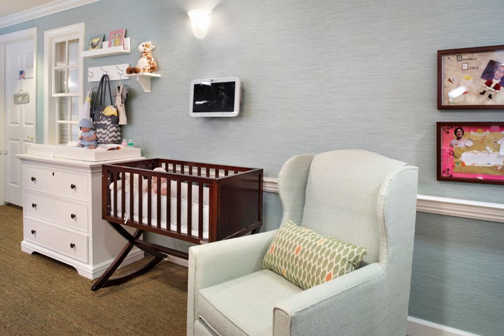 A cozy nursery featuring a crib and a comfortable rocking chair with decorative shelves.