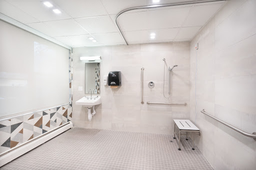 A modern accessible bathroom featuring a shower, sink, and amenities for individuals with mobility needs.