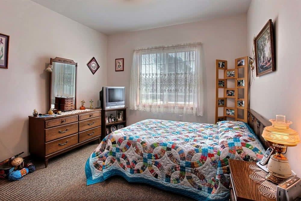 A cozy bedroom with a colorful quilt, vintage furniture, and a charming atmosphere.