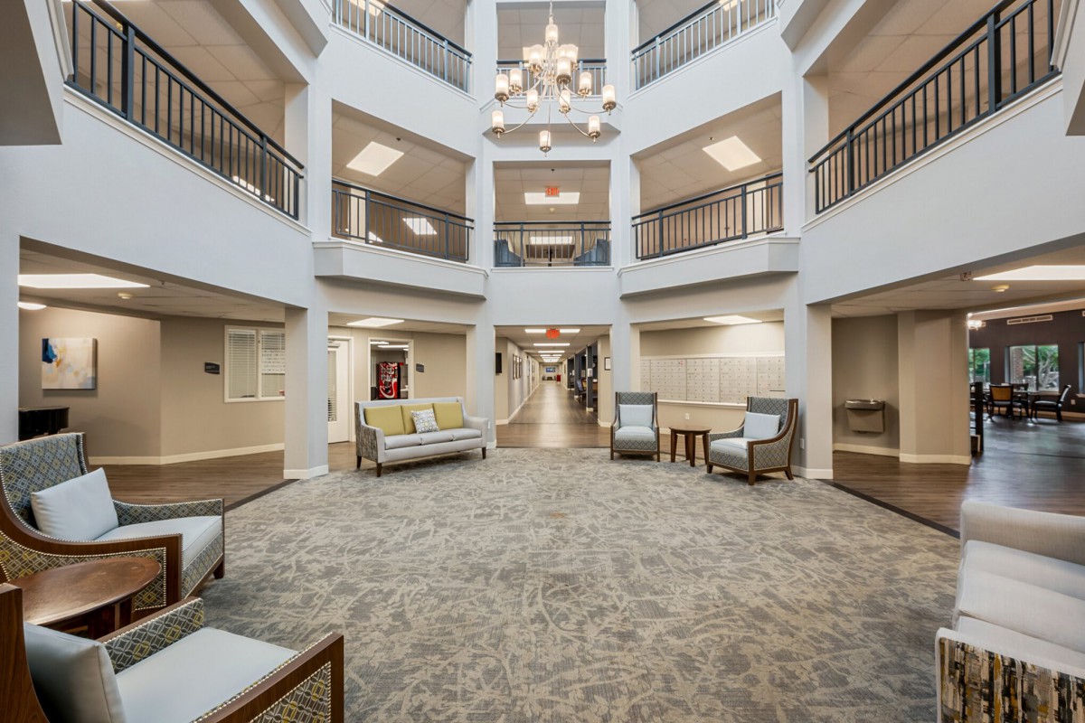 A spacious multi-level lobby with elegant furnishings and a central chandelier.