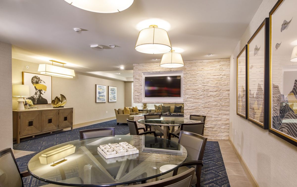 A modern lounge area featuring glass tables and stylish lighting fixtures, complemented by wall art.