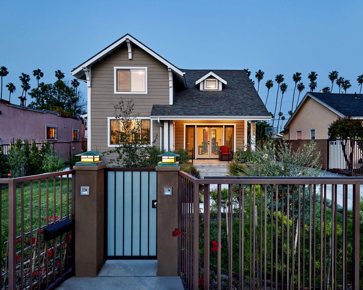 A charming residential house with a front garden and gate, captured in the evening.