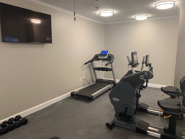 A small gym room featuring a treadmill and a stationary exercise bike.
