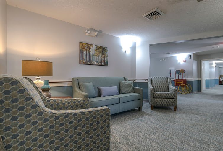 A cozy living room featuring a sofa, armchairs, a coffee table, and artwork on the wall.
