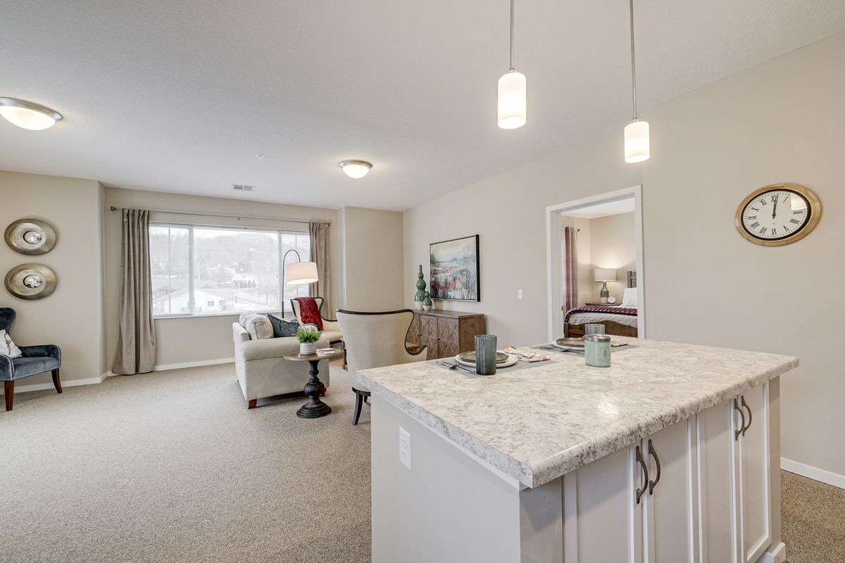 A modern open-plan living area with a kitchen and cozy seating space, illuminated by natural light.