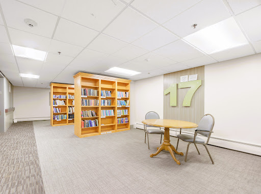 A quiet library space featuring wooden bookshelves, a table, and chairs perfect for studying.