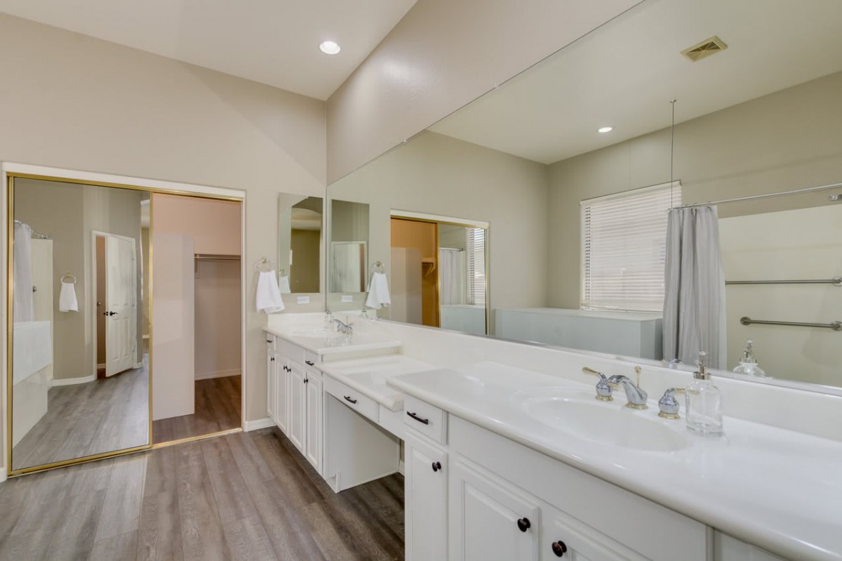 A modern bathroom with a large mirror and dual sinks on a white vanity.
