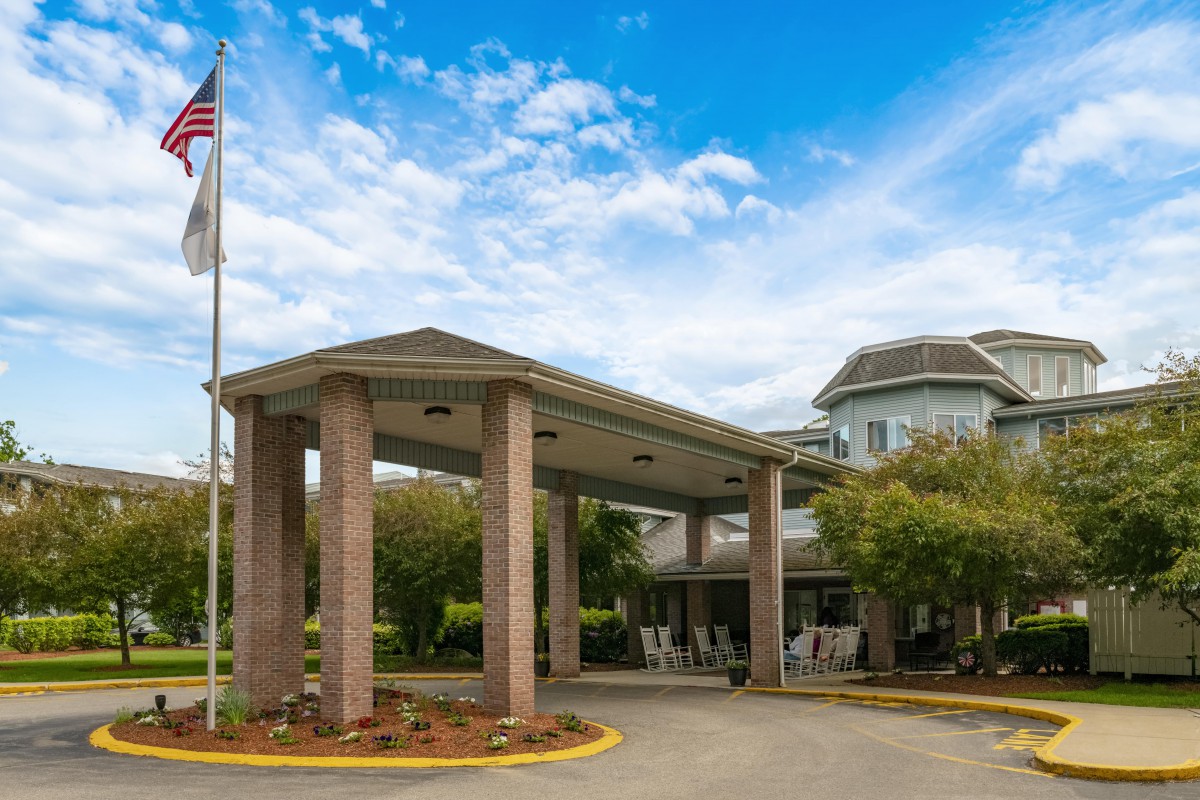 Entrance of a building with columns and an American flag nearby.
