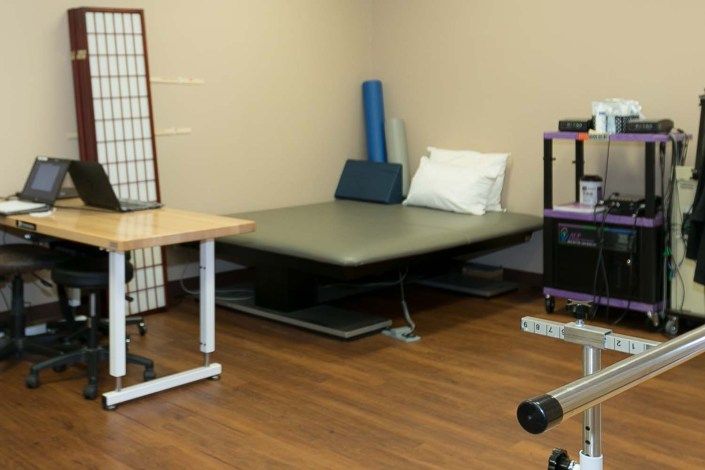 A well-equipped physical therapy treatment room with a therapy bed and exercise equipment.